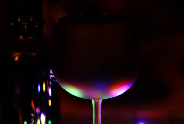 Yumuşak renkli ışıkla kısmen aydınlatılmış izole edilmiş siyah kokteyl camına bakın. Bulanık şişe arkaplanı.