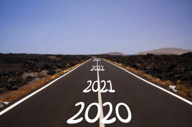Uzun sert, taşlı, başarılı yol kavramı: 2020, 2021, 2022, 2023 yıllarındaki kurak volkanik arazide sonsuz asfalt yola bakış