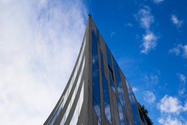 Modern gökdelenin keskin kenarına alçak açılı bir bakış açısı var. Mavi gökyüzüne karşı kıvrımlı bir cephe ve bulutlar - Duesseldorf, Almanya