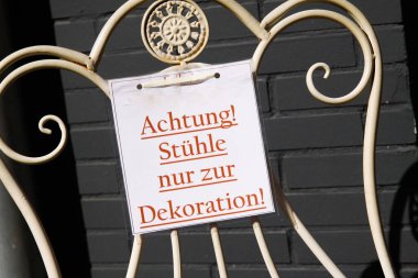 Satılık değil. Antika metal koltukta kırmızı mesajla kartondan görüntüle (Almanca metin: Dikkat! Sadece dekorasyon için sandalyeler - Almanya