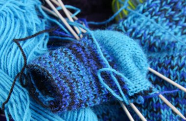 Dikiş malzemeleri: Mavi örgü bebek çoraplarını yün toplarla birlikte sepete koy