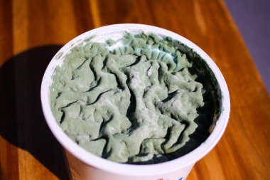 Green living landscape in dairy products pot: Makro close up of isolated moldy yoghurt cup with green mold fungi on surface exceeded expiry date clipart
