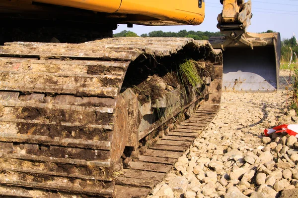View along crawler drive chassis of dirty excavator on shovel with stony gravel ground - Viersen, Germany
