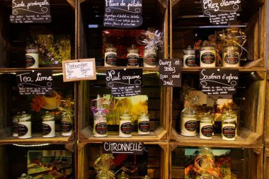 Roussillon (Provence), Fransa - 2 Ekim. 2019: Tipik ürünlerle birlikte Fransız dükkanının içinde ahşap şarap kutularının yaptığı rafa bakın. Kokulu mumlarla dolu cam kavanozlar (bujiler) arka arkaya sunuluyor.