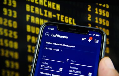 Viersen, Almanya - 6 Temmuz. 2020: Cep telefonunun Lufthansa uçuş rezervasyon uygulaması ile kapatılması. Bulanık çıkış tahtası arka planı. Lufthansa kelimesine odaklan.)