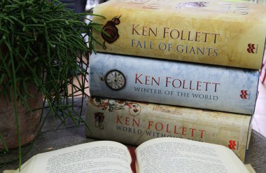 Viersen. Almanya - 9 Temmuz. 2020: Ahşap masada açık bir kitap, Ken Follet romanları ve yeşil bitki yığını