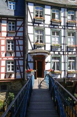 Monschau, Almanya (Eifel) - 9 Temmuz. 2020: Ortaçağ köyünün merkezindeki ahşap çerçeve evindeki köprüye bakın