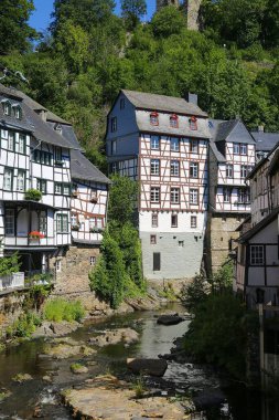 Monschau, Almanya (Eifel) - 9 Temmuz. 2020: Ortaçağ köyünün merkezinde kereste çerçeveli evler ile nehir manzarası