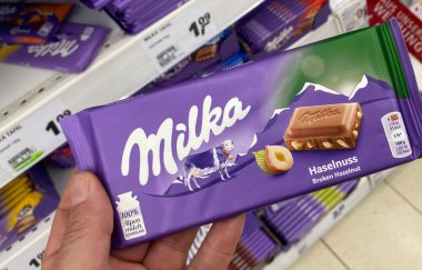Viersen, Almanya - 9 Temmuz. 2020: Alman süpermarketinde Milka çikolatalı çikolatayı elinde tutarken