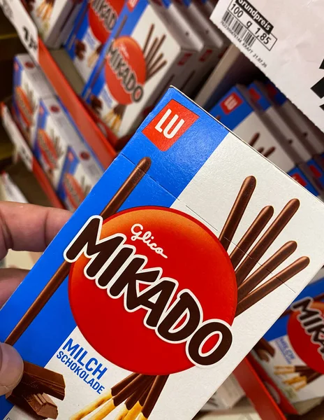 Viersen, Almanya - 9 Temmuz. 2020: Alman süpermarketinde rafın önünde el ele tutulan mikado çikolatalı karton kutunun görüntüsü