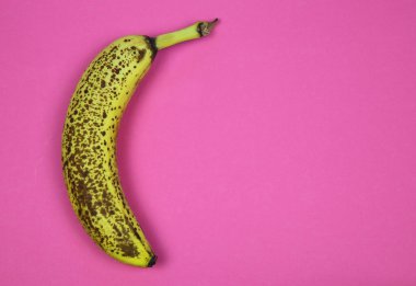 İzole edilmiş, olgun, kahverengi, pembe arkaplan ve metin için boş kopya alanı olan bir muz üzerinde görüntüle