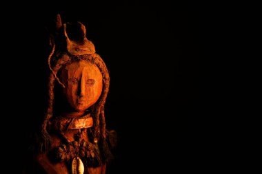 İzole edilmiş Himba kadın ahşap heykeli, koyu siyah arka planda.