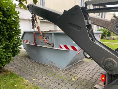 Viersen, Almanya - 17 Ekim. 2020: Özel evin garaj girişine organik bahçe atıkları için konteynır koyan vinç görüntüsü