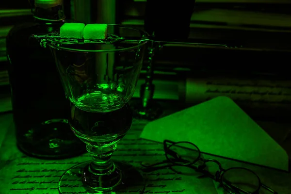 在漆黑的绿色夜色中凝视孤立的苦艾酒和酒瓶 — 图库照片