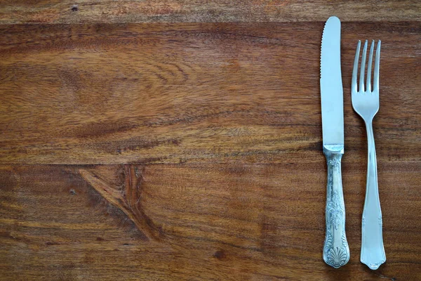 暗い木製のテーブルトップの背景には 古いフォークと古いナイフとテキスト用のスペースがたくさんあります — ストック写真