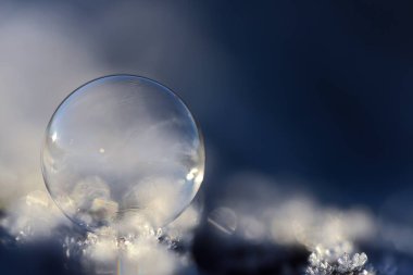 Beyaz ve mavi arkaplan ve metin için alan ile kar üzerinde parlak şeffaf bir sabun kabarcığı ile kış havası