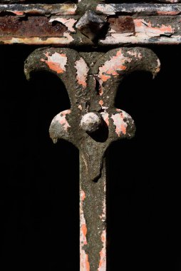 Eski paslı bir çitin yakından ve detaylı görüntüsüyle yıpranmış süs ve boya soyuluyor ve çürüme belirtileri gösteriyor.