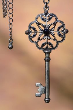 Eski bir antika metal anahtar arka planda gümüş bir zincire asılı.
