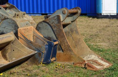 Kullanılmış ve kirli kazıcı kürekleri Dünya 'da terk edilmiş bir inşaat sahasında yatıyor.