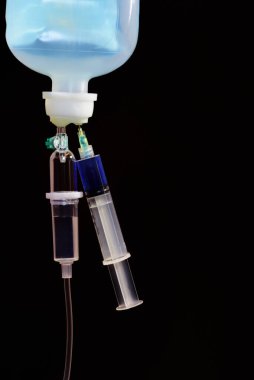 Dikey metin için tıpta ve mekanda siyah bir arkaplan ile mavi sıvı içeren bir şırınga içeren bir infüzyon sistemine yakın çekim