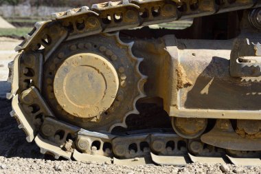 Metal tekerlerin ayrıntıları ve yakın plan çekimleri ve toprak ve toprakla kaplı bir inşaat sahasında kazıcı tekerleği.