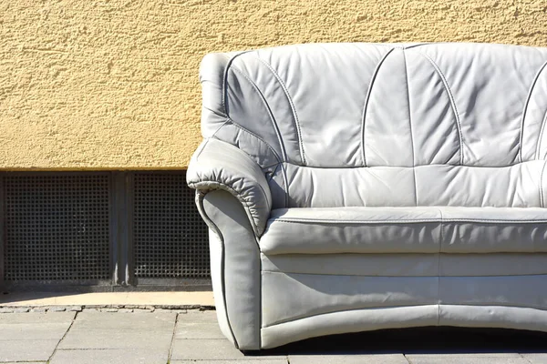 Almanya 'da yol kenarında bodrum penceresi olan bir ev duvarının önünde duran eski, parlak, deri bir kanepe sizi oturmaya davet ediyor.