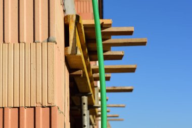 Taze yanmış tuğlalar ve mavi gökyüzünün önündeki bir bina duvarı.