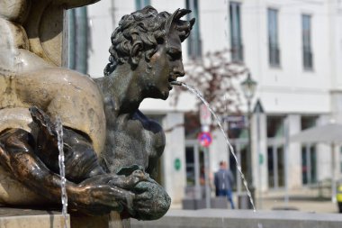 07 / 18 / 2019, Almanya, Augsburg 'da, Herkül Çeşmesi' ndeki bir figür şehrin tarihi evlerinin önüne bir fıskiye püskürtüyor.