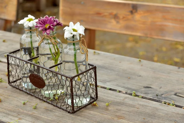 Dışarıda, Bavyera 'da bir bira bahçesindeki ahşap bir masada çiçeklerle süslenmiş şişeler sonbaharda tarihi bir arkaplanda bekliyorlar ve misafirlerini bekliyorlar.