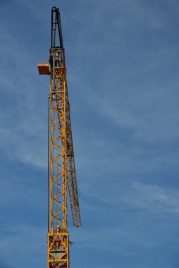 Arkasından portre şeklinde sarı metal bir vinç açık alanlı mavi bir gökyüzüne karşı.