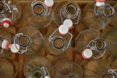 Yukardan şeffaf cam şişeler açık kapaklı ahşap bir kutuda.