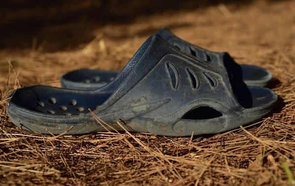 used old dirty plastic shoes stand on a dry meadow in summer
