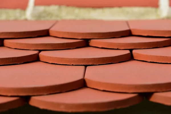 Close-up of flat red clay roof tiles layered on a roof.