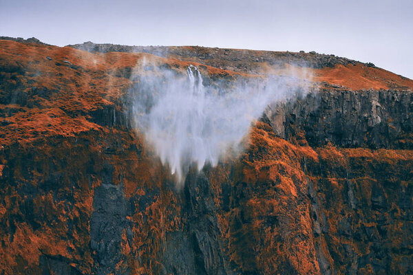 Dramatic scne of water from waterfall being blown away by strong and gusty storm winds off the steep cliff located in nearby Seljalandsfoss in Southern Iceland. Here photographed in early October 2019.