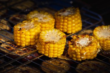 Açık hava ızgarasında birkaç tane taze sarı kahverengi mısır koçanı pişiriyorum..