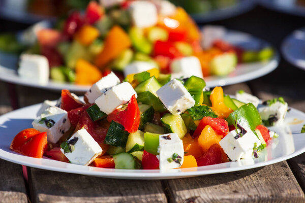 Greek salad of fresh cucumber, tomato, sweet pepper, lettuce, red onion, feta cheese and olives with olive oil. Healthy food