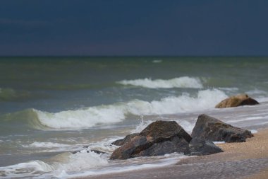 Güçlü dalgalar kayalık bir sahilde eziliyor..