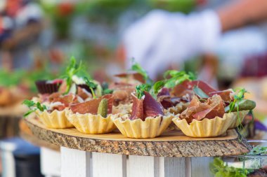 exquisite beautiful serve prosciutto in baskets on a wooden slice. Catering