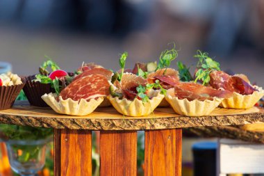 exquisite beautiful serve prosciutto in baskets on a wooden slice. Catering