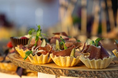 exquisite beautiful serve prosciutto in baskets on a wooden slice. Catering