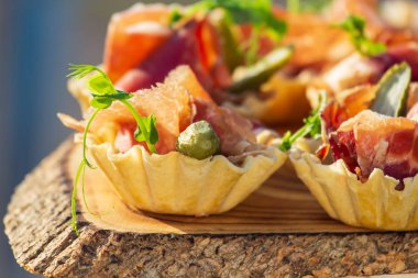 exquisite beautiful serve prosciutto in baskets on a wooden slice. Catering
