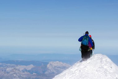 Bir grup dağcı karla kaplı bir dağ tepesine tırmanıyor