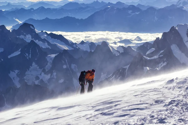 Een groep bergbeklimmers klimt naar de top van een besneeuwde berg — Stockfoto