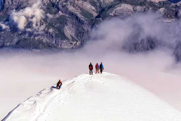 Een groep bergbeklimmers klimt naar de top van een besneeuwde berg — Stockfoto