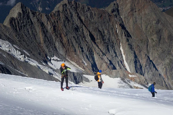 Een groep bergbeklimmers klimt naar de top van een besneeuwde berg — Stockfoto