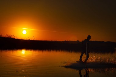 Wakeboarder günbatımı üzerinde hileler yapmak