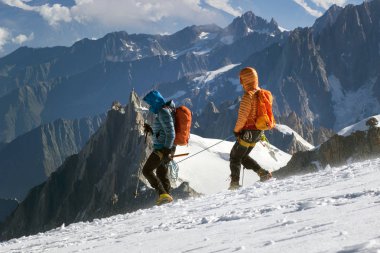 Kar alanı buz baltaları ve kask ile bir iple bağlı olan dağ tırmanma tırmanıcı bağlı.