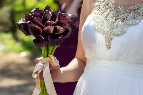 Female hands with a bouquet of burgundy flowers.