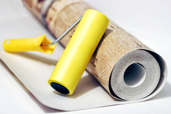 Composition tools for home repair and interior renovation indoors. Rolls of wallpaper, roller