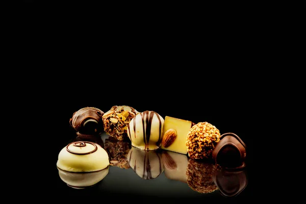 Chocolade Snoepjes Een Zwarte Spiegelend Oppervlak Getrempeerd Met Kokos Chips — Stockfoto